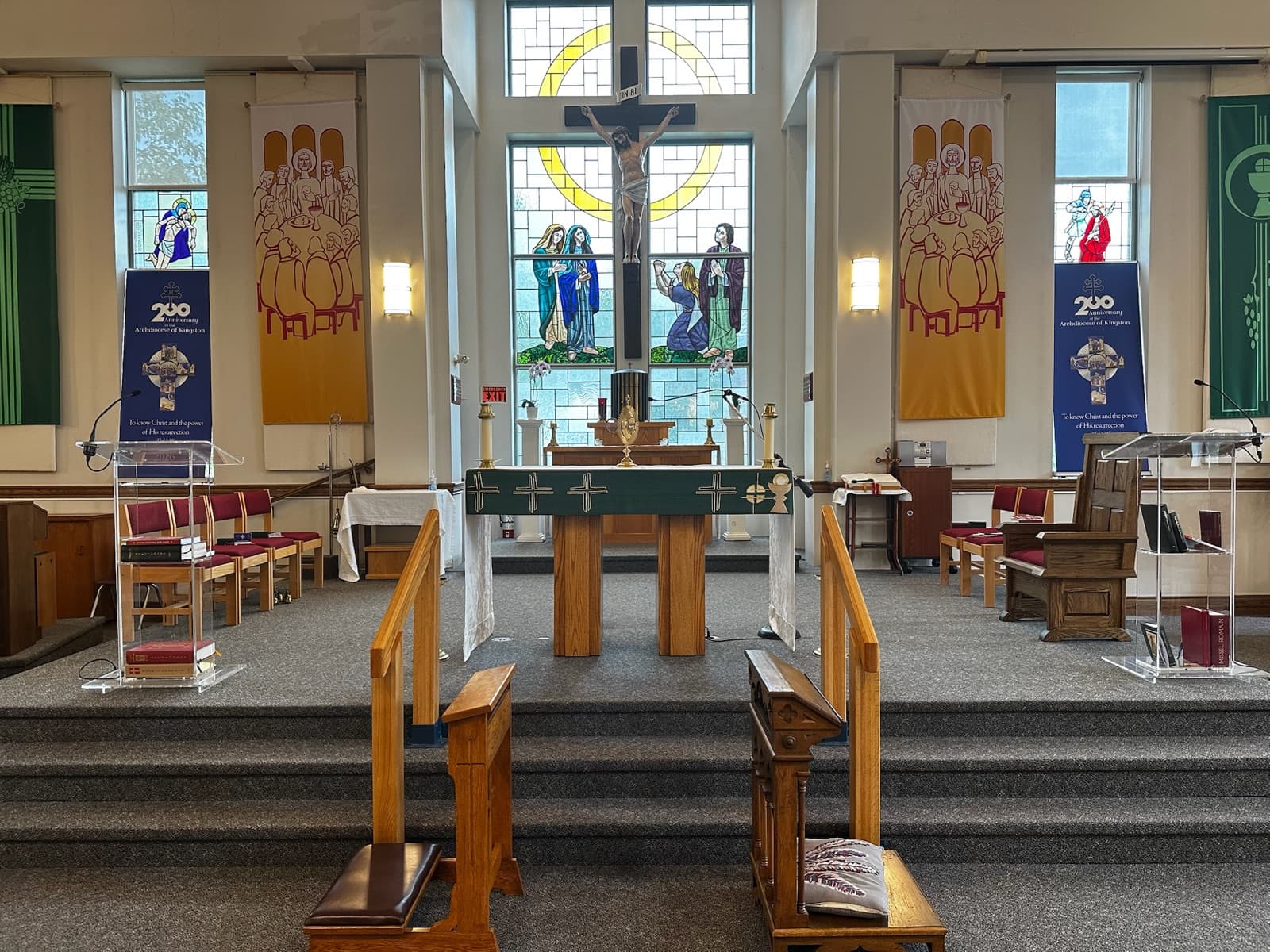 The sanctuary: a stone altar flanked by reading stands, beneath a crucifix and a stained-glass window of the Crucifixion.